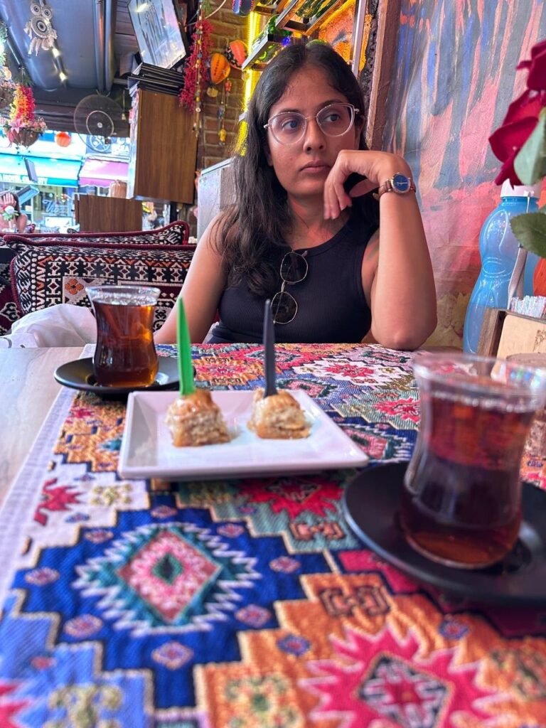 Sanju at a café table with Turkish tea and baklava